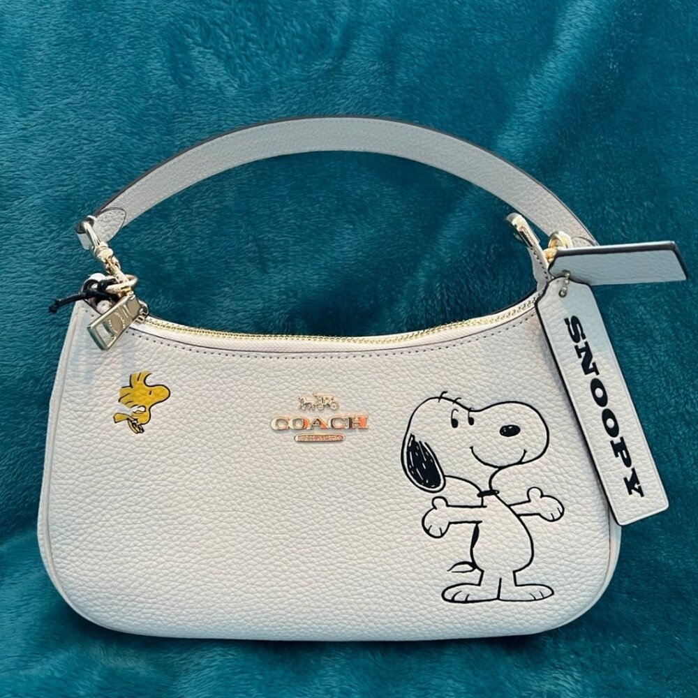 Coach X Peanuts Teri white shoulder bag with Snoopy pattern.